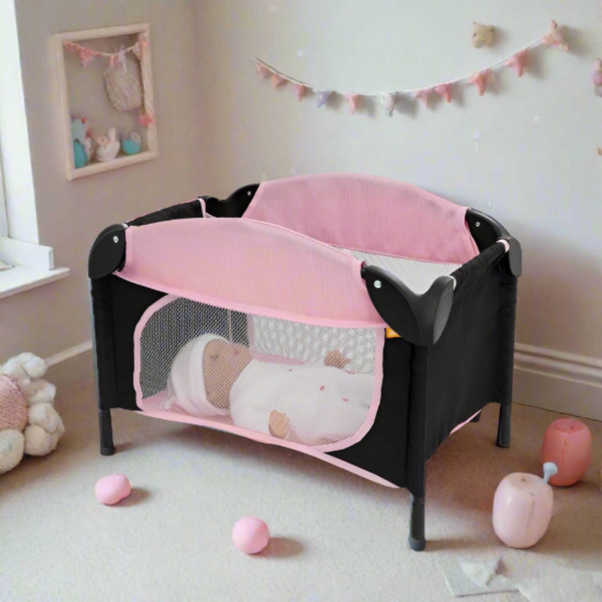 Joie Sleep &amp; Dream Dolls Travel Cot, a compact and foldable design in pink and grey, featuring breathable mesh sides and a sturdy frame, ideal for children to use for their dolls during playtime and travel