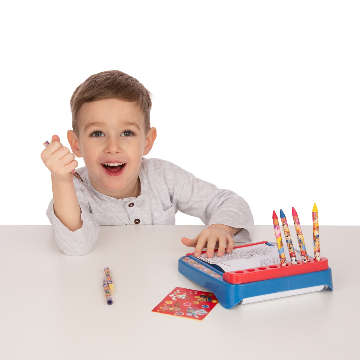 Child using a colouring book with crayons on a white background
