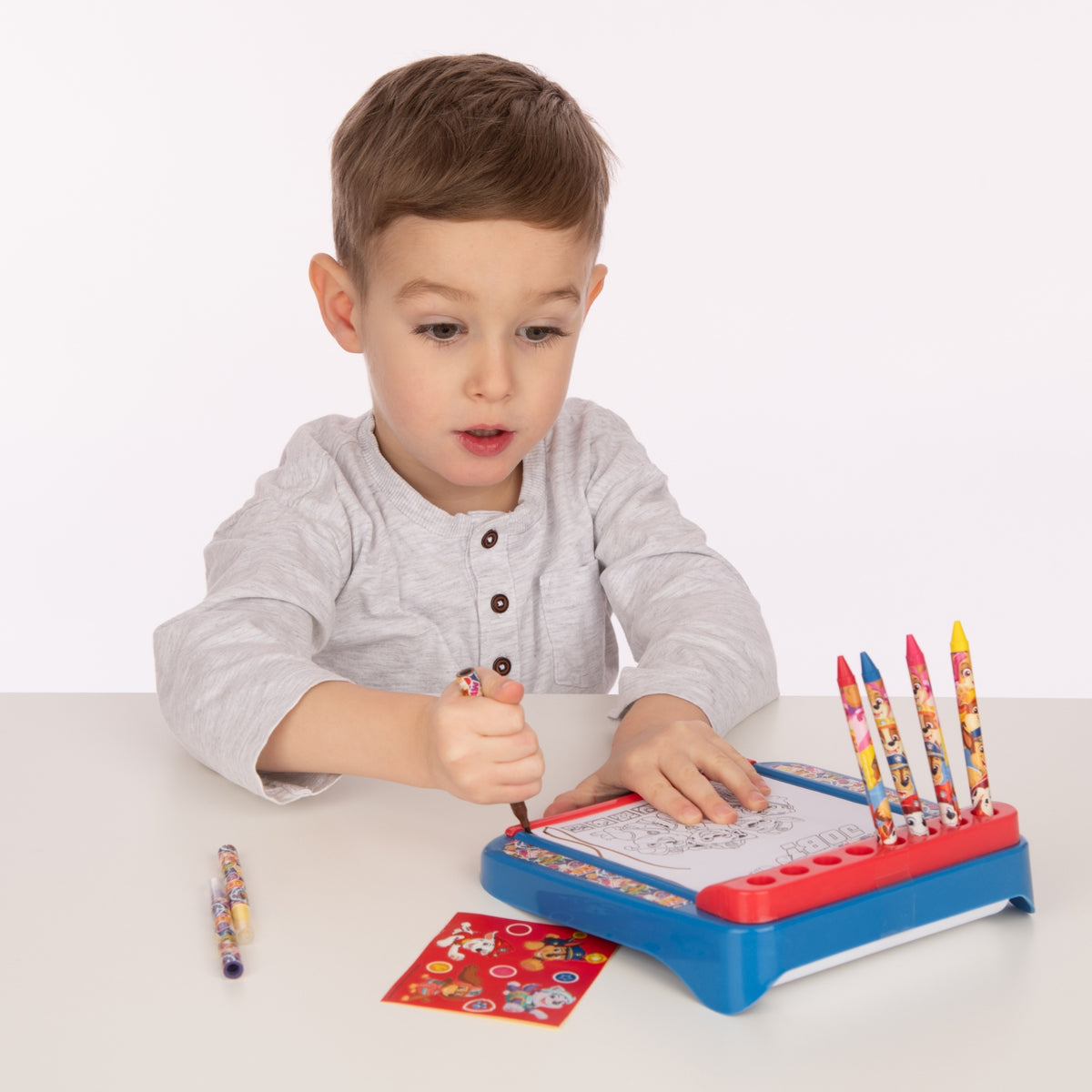 Child using a colouring board with coloured pencils on a white background