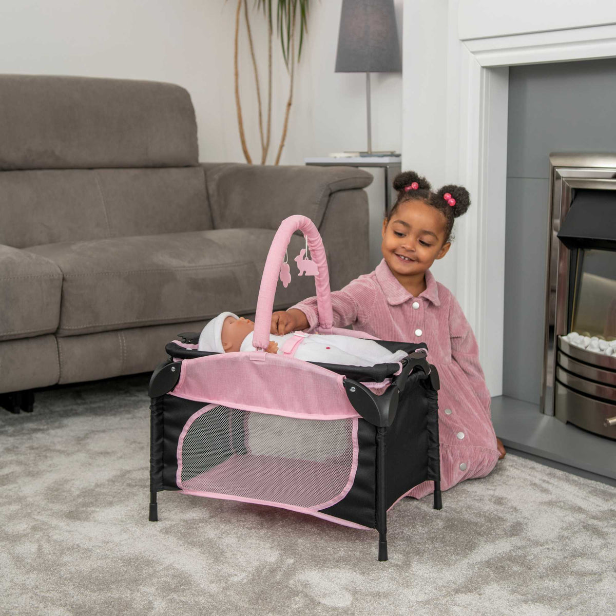 Joie Sleep &amp; Dream Dolls Travel Cot, a compact and foldable design in pink and grey, featuring breathable mesh sides and a sturdy frame, ideal for children to use for their dolls during playtime and travel