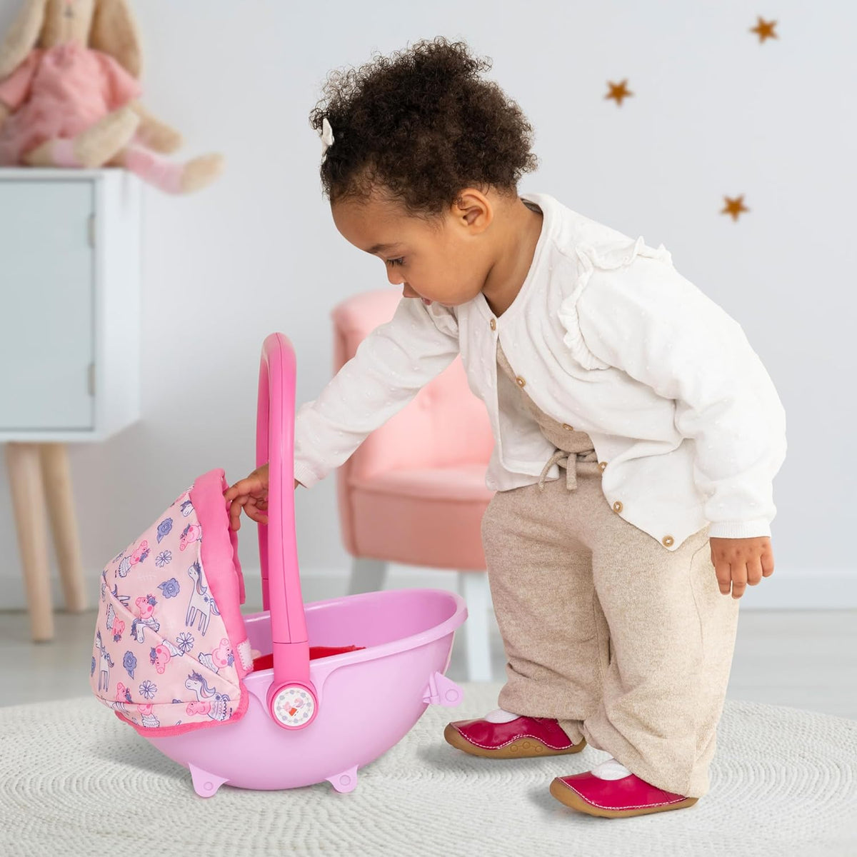 A Peppa Pig 4-in-1 Pram in light pink with a contrasting pink frame, adorned with Peppa Pig stickers on the wheels and frame. Includes an adjustable hood and removable apron, shown as a pushchair.