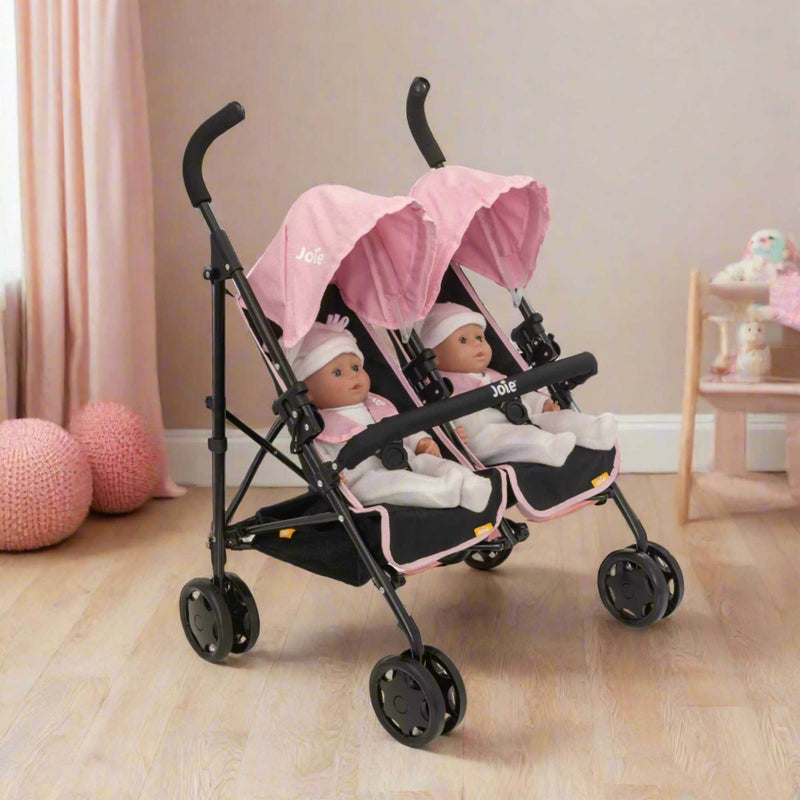 Joie Aire Twin Dolls Stroller in pink and black, designed with side-by-side seating for two dolls, adjustable handle height, swivel wheels, and a large storage basket, ideal for children to enjoy twin doll outings.