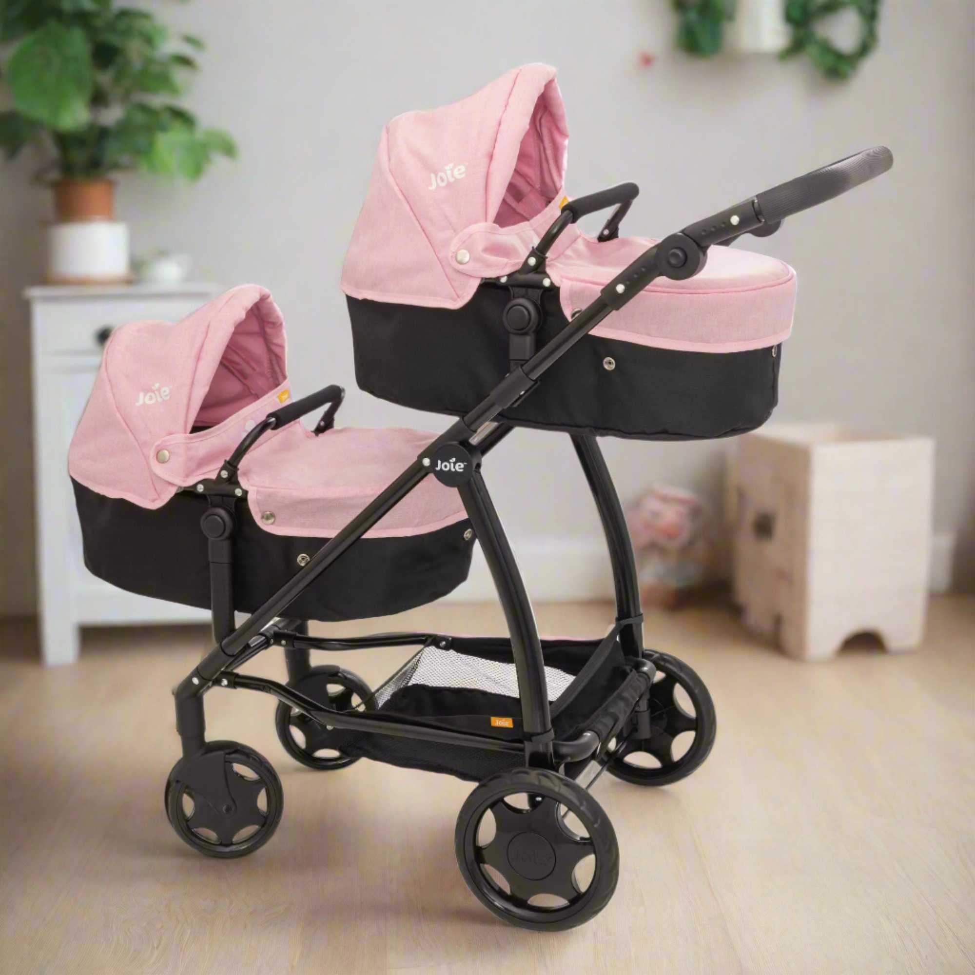 Joie Evalite Twin Dolls Pram with 9 play modes, featuring a stylish design in pink and black, adjustable handle height, swivel wheels, and a large storage basket, perfect for versatile and imaginative play with dolls.
