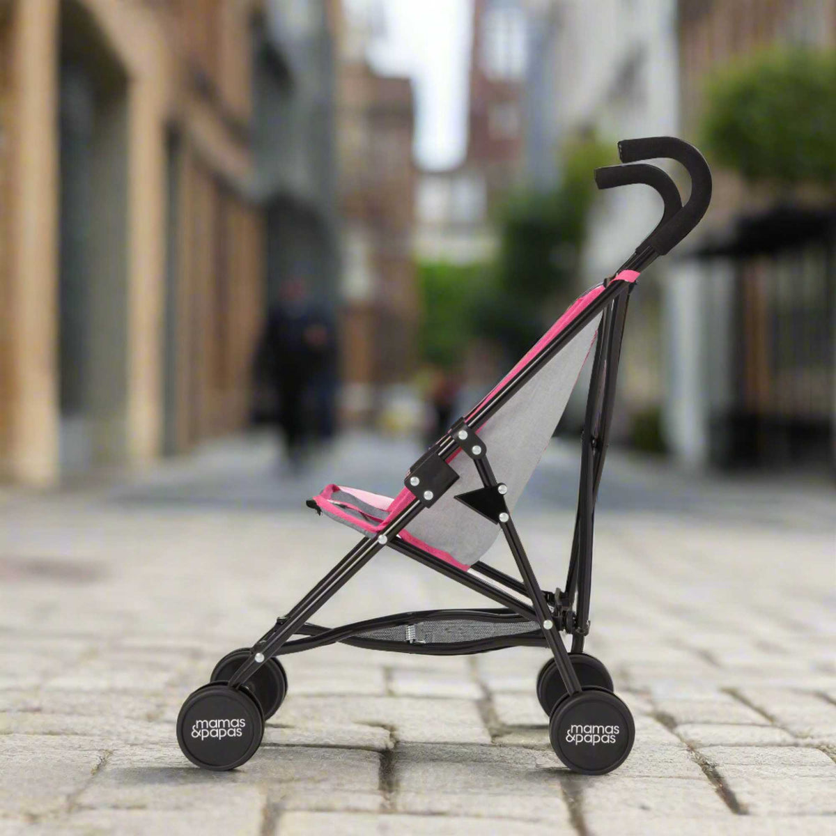 Mamas &amp; Papas Junior Doll Stroller in pink and grey, featuring a foldable and lightweight design for easy storage and portability, ideal for children&#39;s imaginative play with dolls.