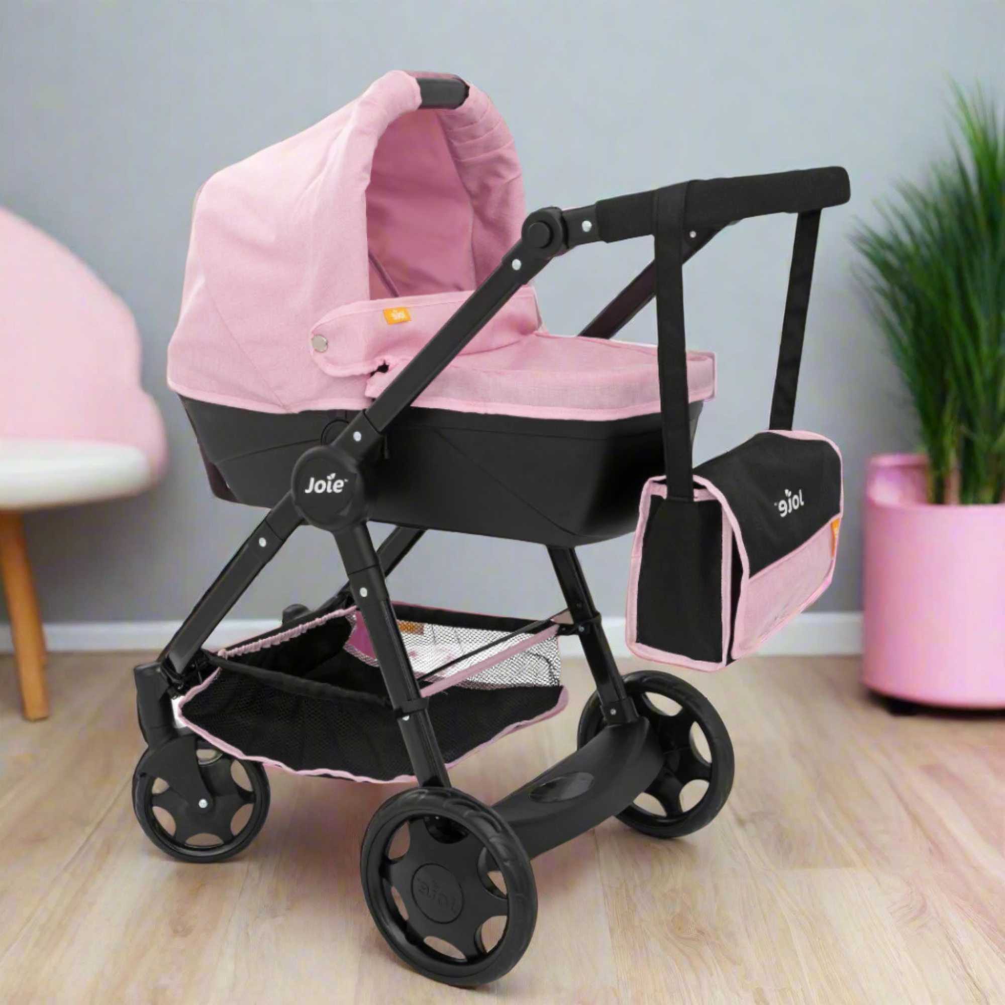 Joie Mytrax Dolls Pram in pink and black, featuring a realistic design with adjustable handle height, swivel wheels, and a large storage basket, ideal for children to take their dolls on walks and play pretend.