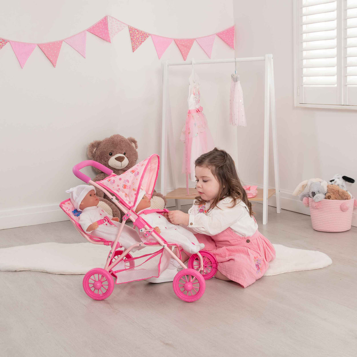 Peppa Pig Tandem Twin Doll Stroller: A pink double stroller with Peppa Pig graphics, designed for carrying two dolls side by side, ideal for toddlers and imaginative play.