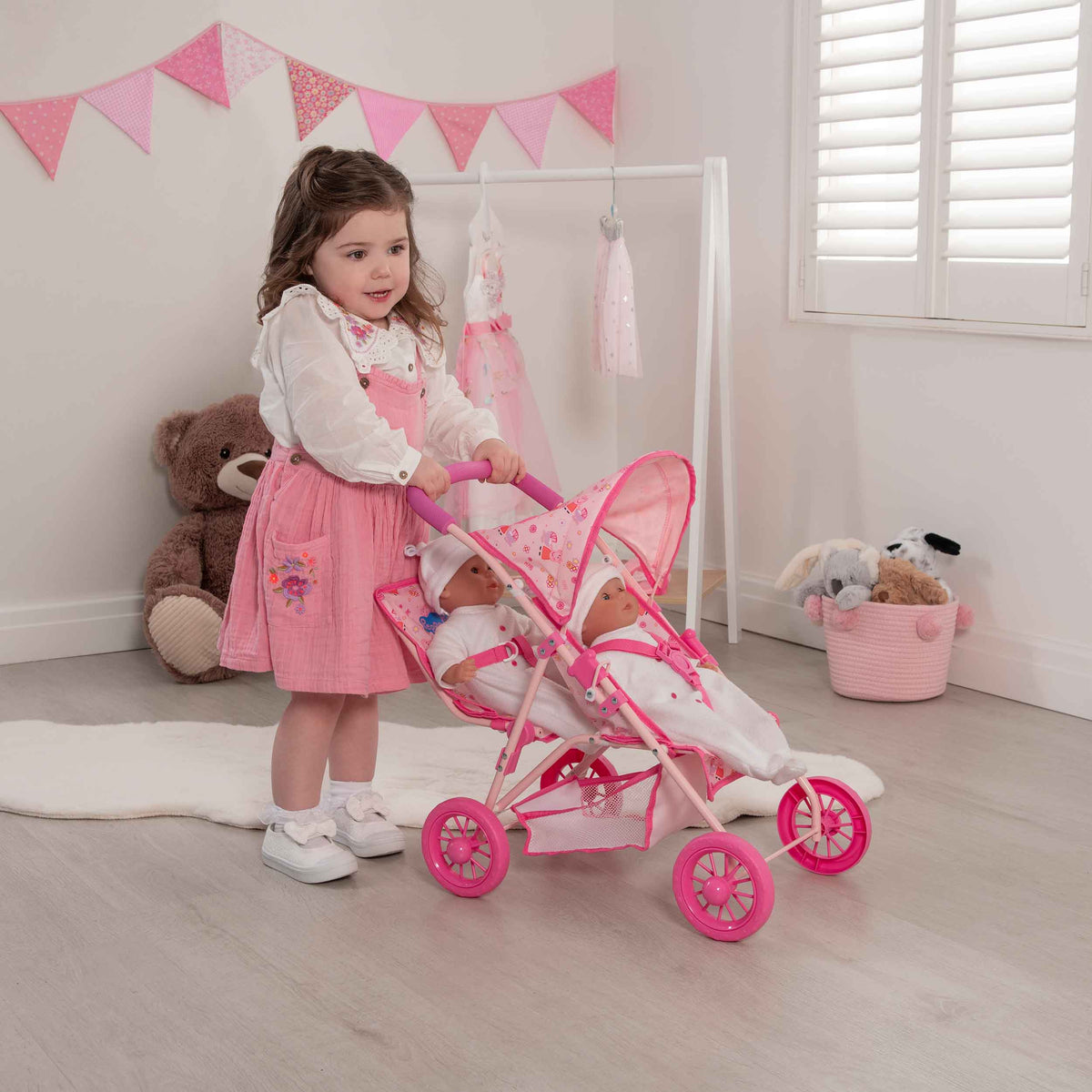 Peppa Pig Tandem Twin Doll Stroller: A pink double stroller with Peppa Pig graphics, designed for carrying two dolls side by side, ideal for toddlers and imaginative play.