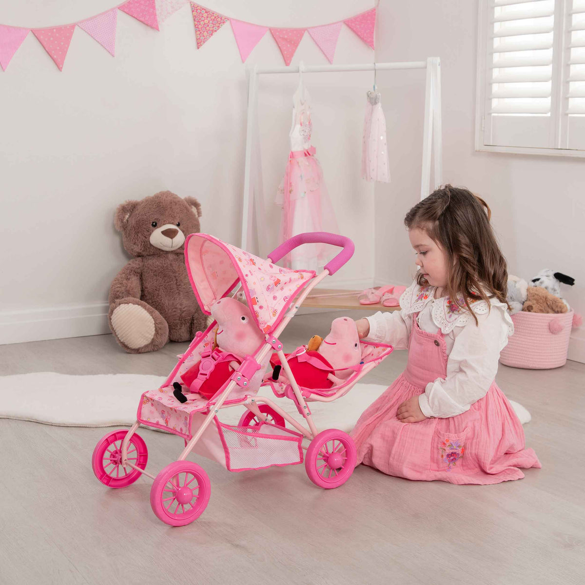 Peppa Pig Tandem Twin Doll Stroller: A pink double stroller with Peppa Pig graphics, designed for carrying two dolls side by side, ideal for toddlers and imaginative play.