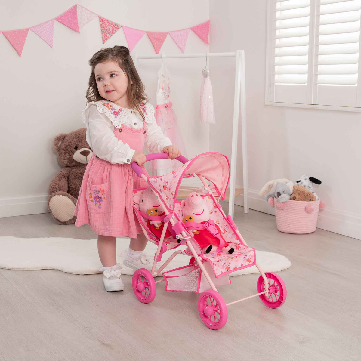 Peppa Pig Tandem Twin Doll Stroller: A pink double stroller with Peppa Pig graphics, designed for carrying two dolls side by side, ideal for toddlers and imaginative play.